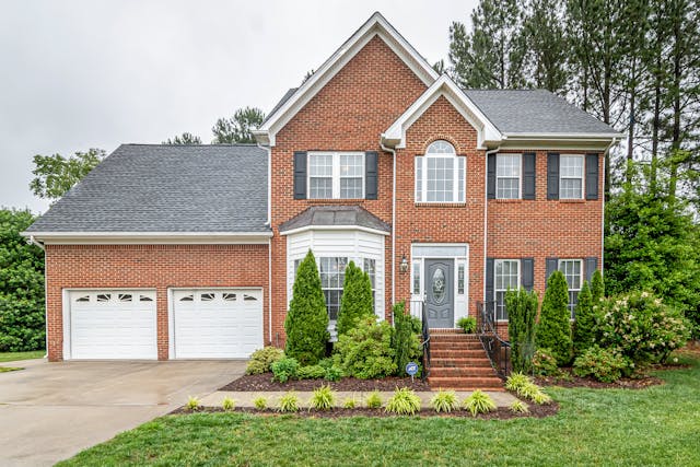 Exterior of a brick home with greenery in the front yard